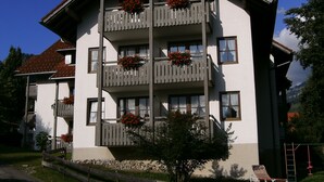 Un edificio a più piani con balconi decorati da cesti di fiori, una scala ben visibile e un cielo sereno.