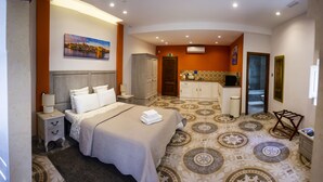 A hotel room with a bed, a nightstand, a dresser, a vanity, and a kitchenette. - Casa Azzopardi Suites (Rabat)