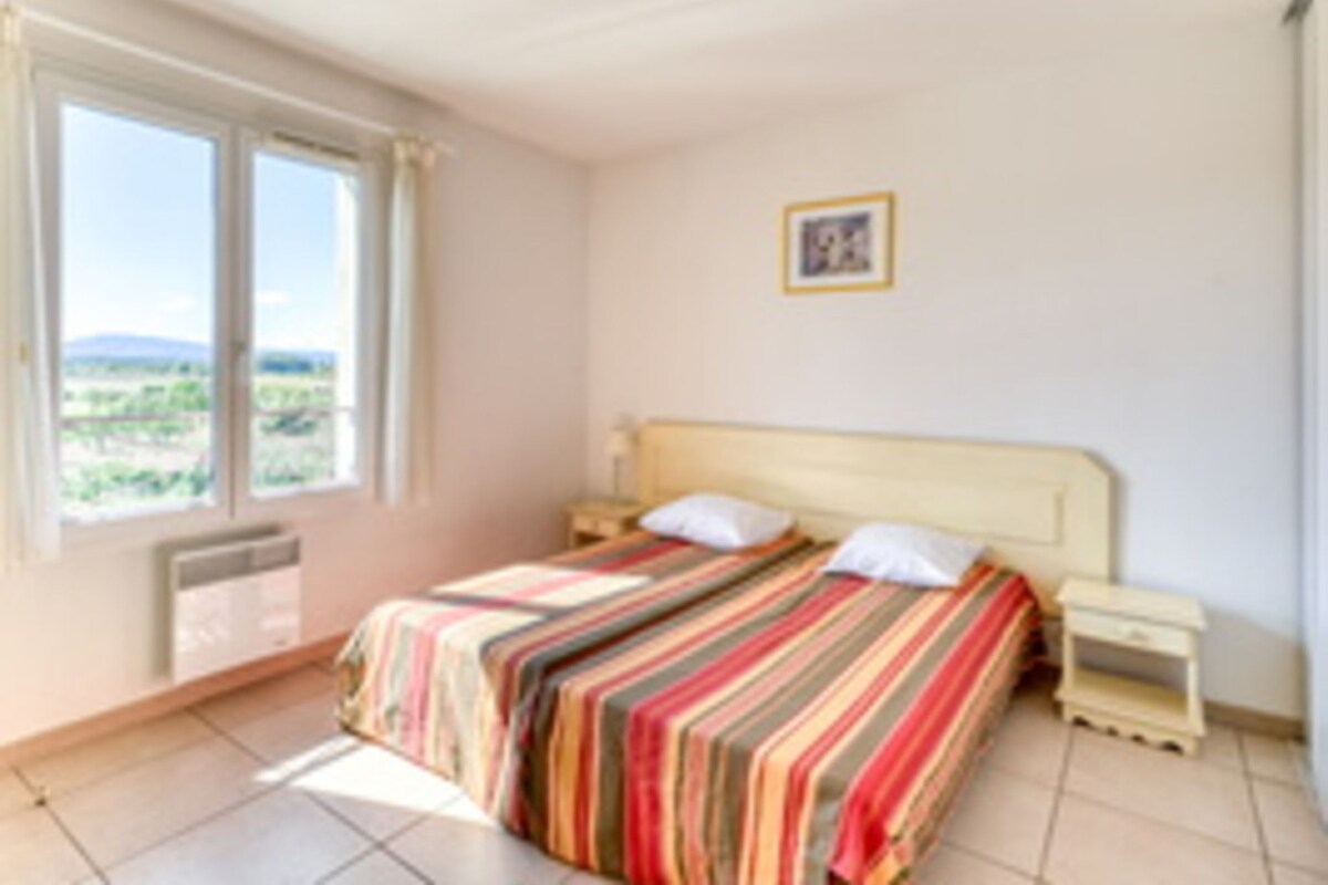 A bedroom with a bed, a nightstand, a window, and a picture on the wall.
