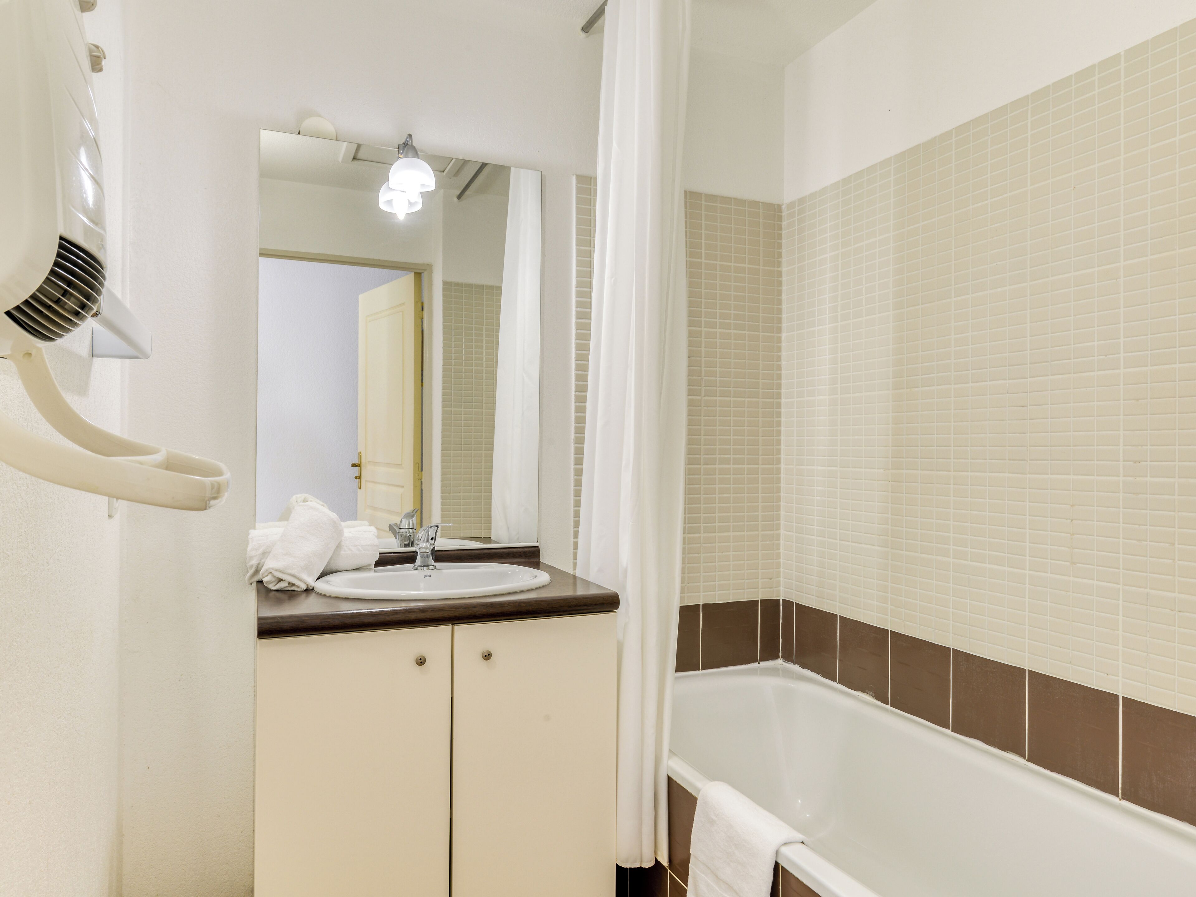 A bathroom with a white sink, a mirror, a shower curtain, and a bathtub.