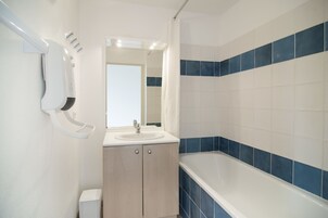 Un baño con lavamanos, espejo y bañera con azulejos azules.