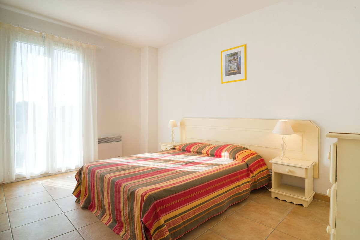 Une chambre à coucher avec un lit, des tables de chevet, une lampe et un tableau encadré au mur.