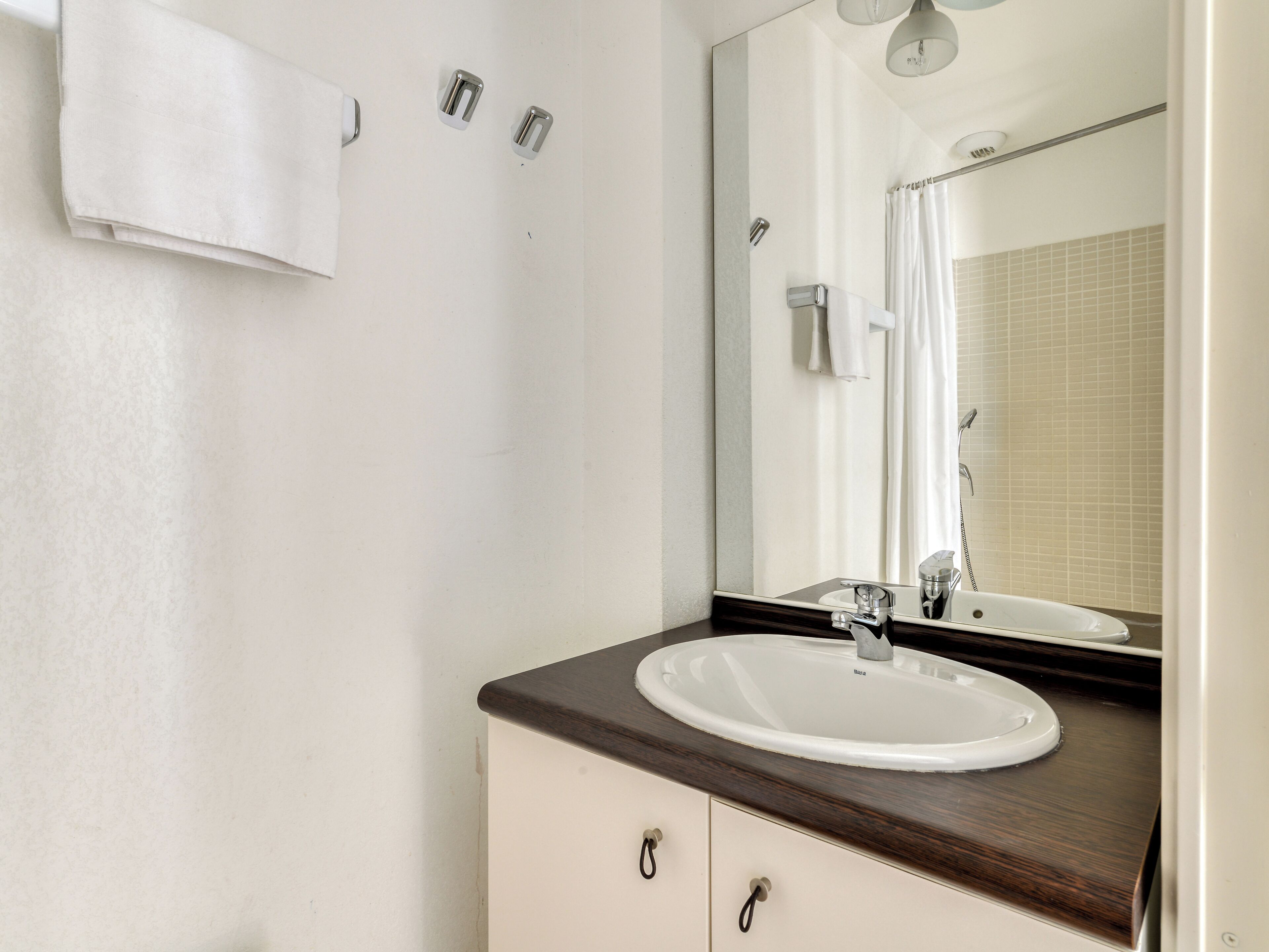 A bathroom with a white sink, a mirror, and a shower.
