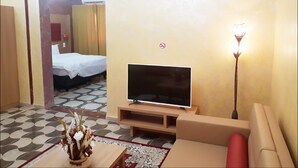 A hotel room with a TV, sofa, and a bed. - Hotel Takialt (Adrar)
