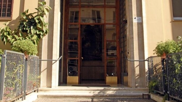 A building entrance with a large wooden door, a small balcony above, and a paved area in front. - Roome B&B (Rome)