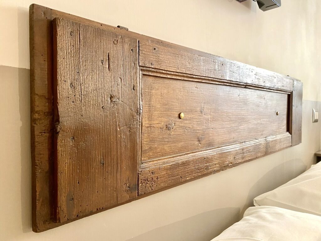 Une tête de lit en bois, au design simple et rustique, fixée au mur.