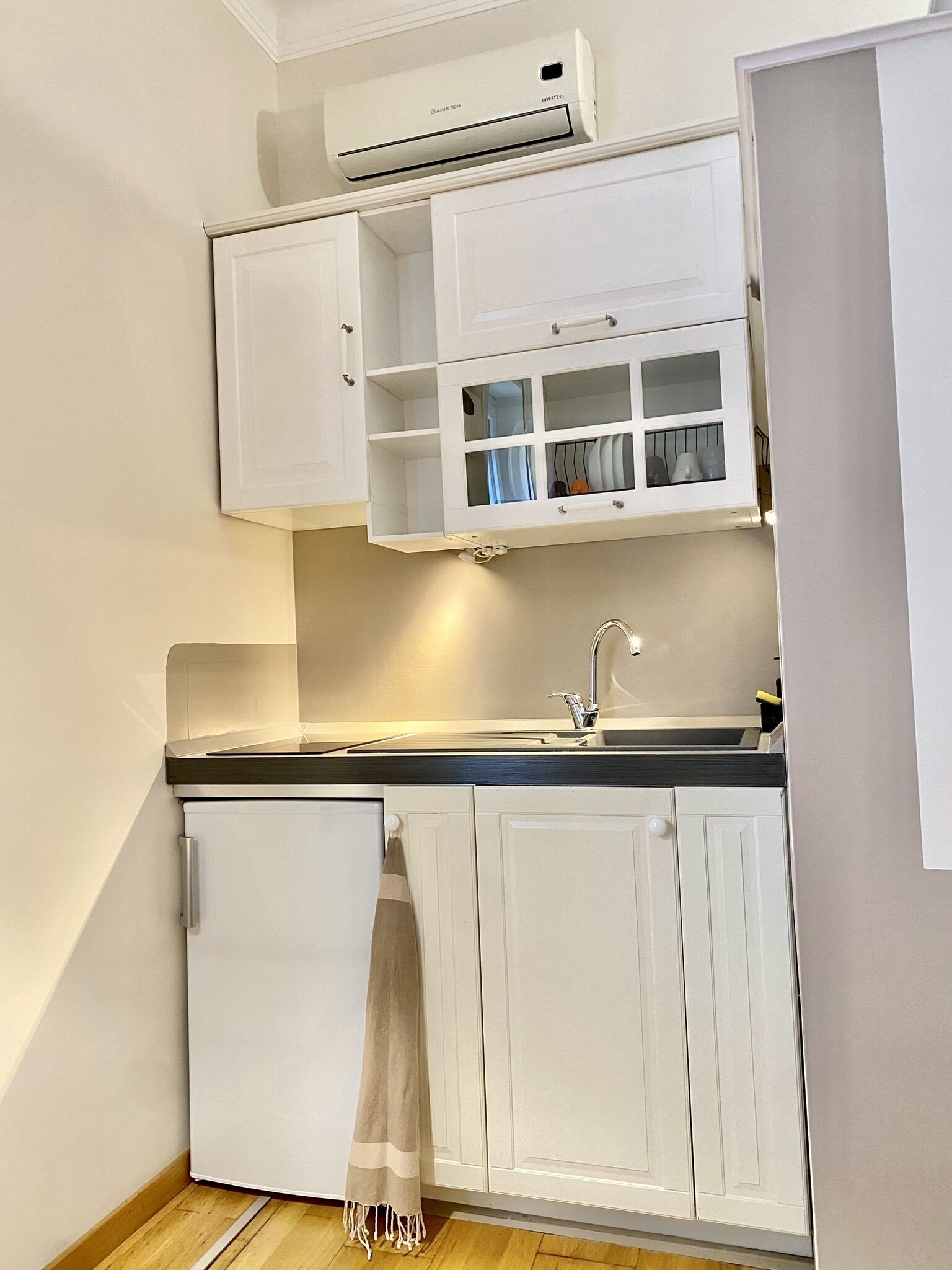 A compact kitchen with white cabinetry, a built-in oven, and a sink.