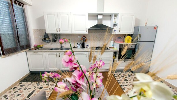 A kitchen with white cabinets, a gas stove, and a refrigerator. - B&B Casa Anna Maria (Porto Sant'Elpidio)