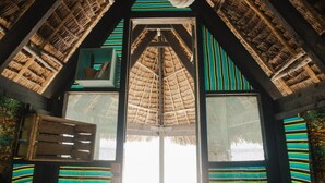 A room with a thatched roof, wooden beams, and striped fabric walls. - Mikadi Beach Camp (Dar es Salaam)