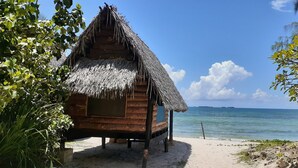 A wooden hut with a thatched roof on a sandy beach, overlooking the sea. - Mikadi Beach Camp (Dar es Salaam)