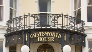 The Chatsworth House entrance with a black iron balcony, steps leading up to the door, and a potted plant on the right. - Chatsworth House Hotel (Llandudno)