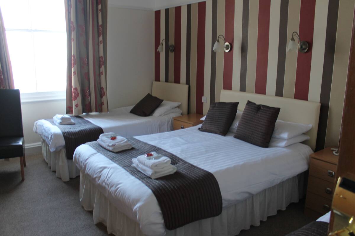 Een hotelkamer met twee eenpersoonsbedden, een groot bed, een bureau en een stoel.