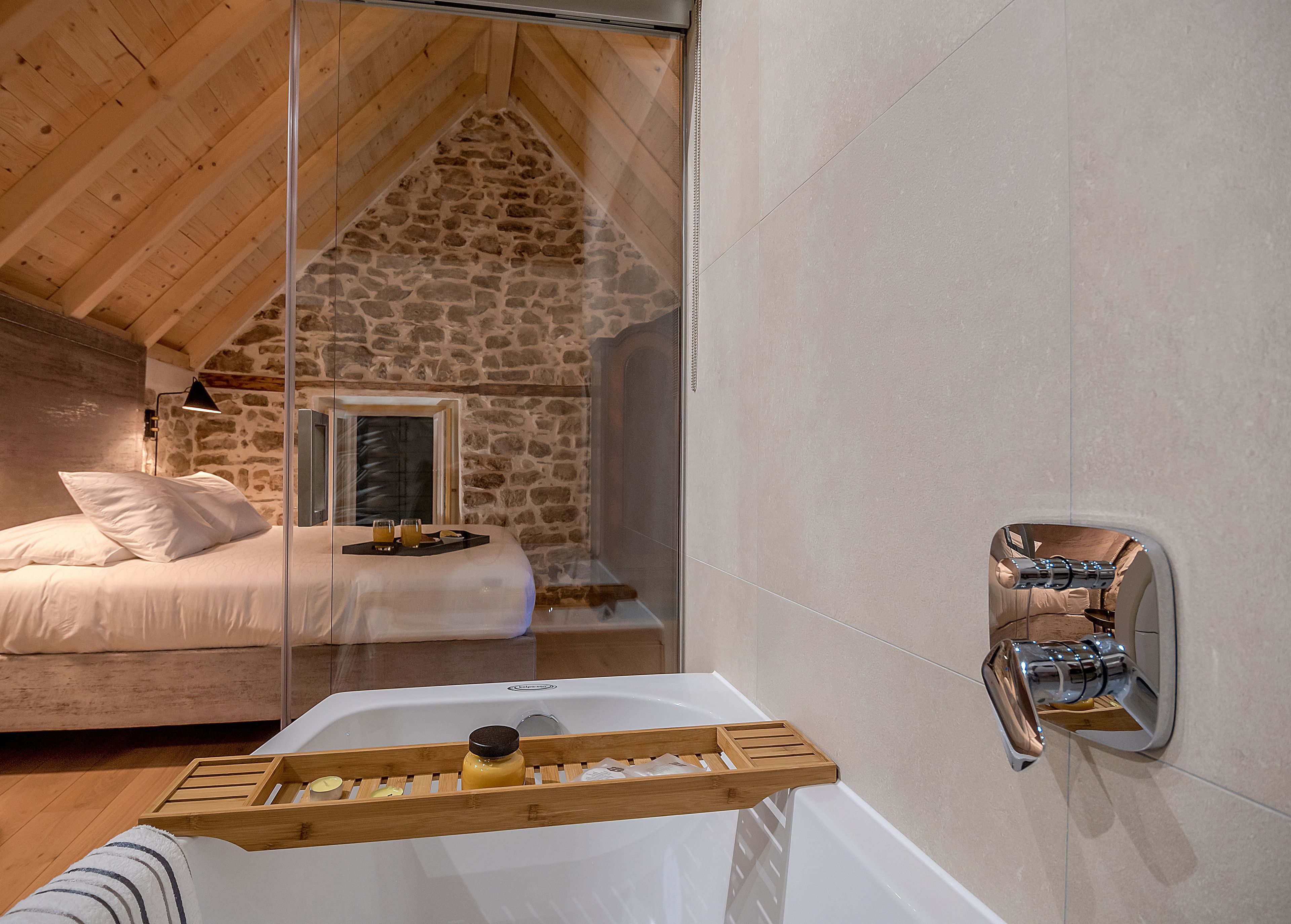 A modern bathroom with a stone wall, a bathtub, and a shower area.