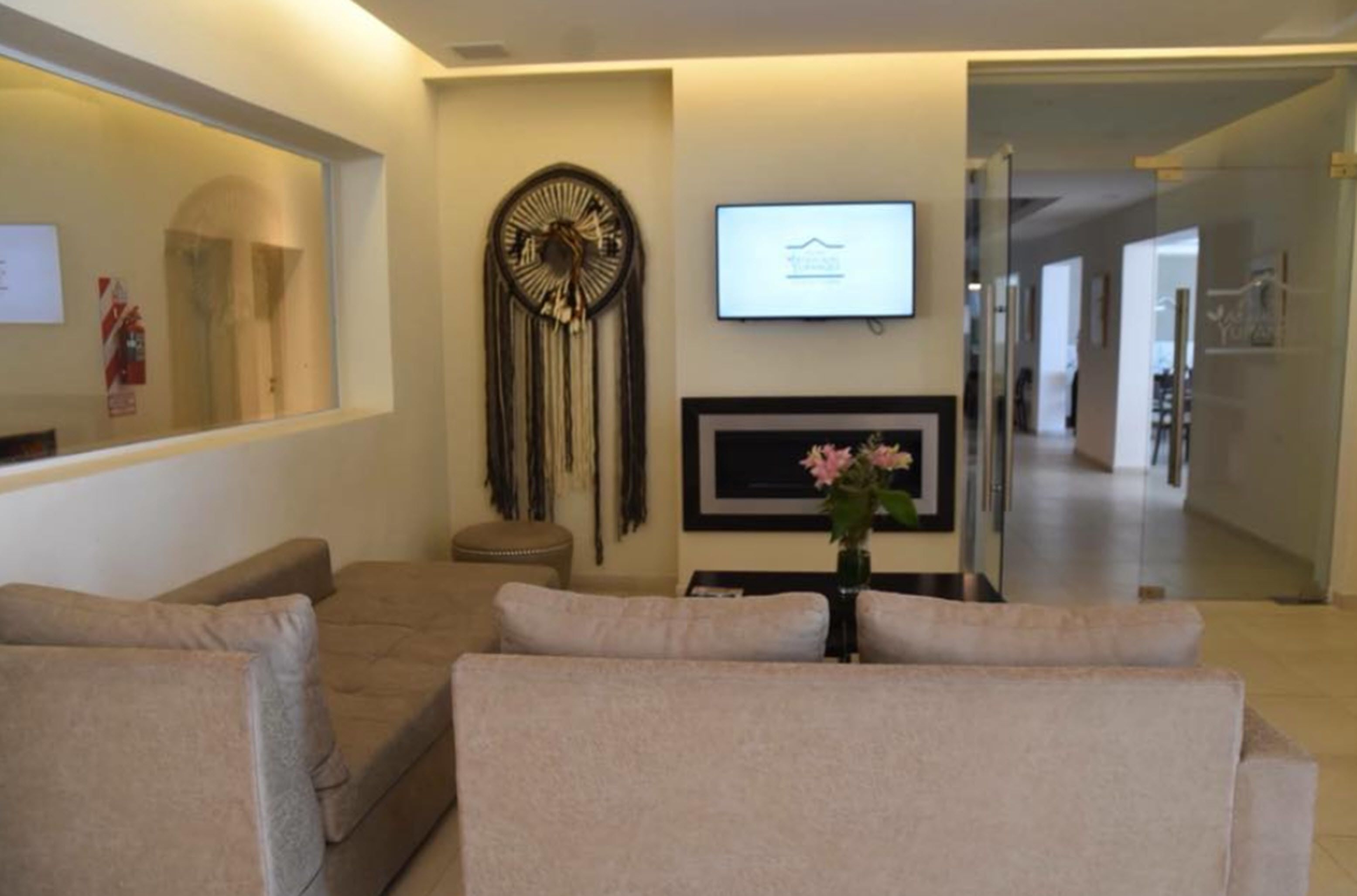 Una sala de estar moderna con un sofá beige, un televisor montado en la pared y un adorno mural.