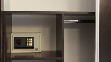 A secure safe with a keypad lock, located in a compartment of a wooden cabinet.