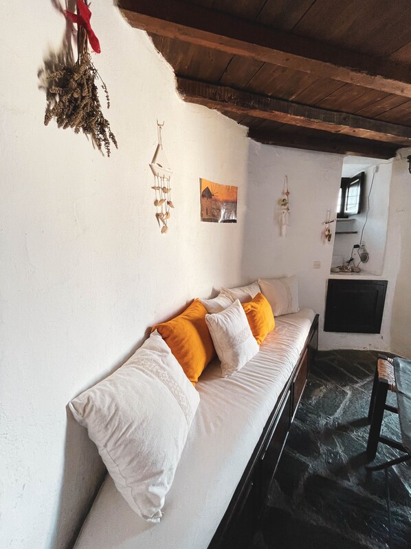 A room with a bed, a wooden ceiling, a wall-mounted TV, and a window.