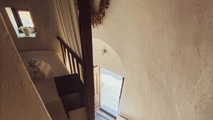 Eine Treppe mit Steinstufen, die zu einem Zimmer mit einem Bett und einem Fenster führt.