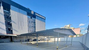 Ein Parkplatz eines Zallon Hotels mit überdachtem Gang und einem Gebäude im Hintergrund.