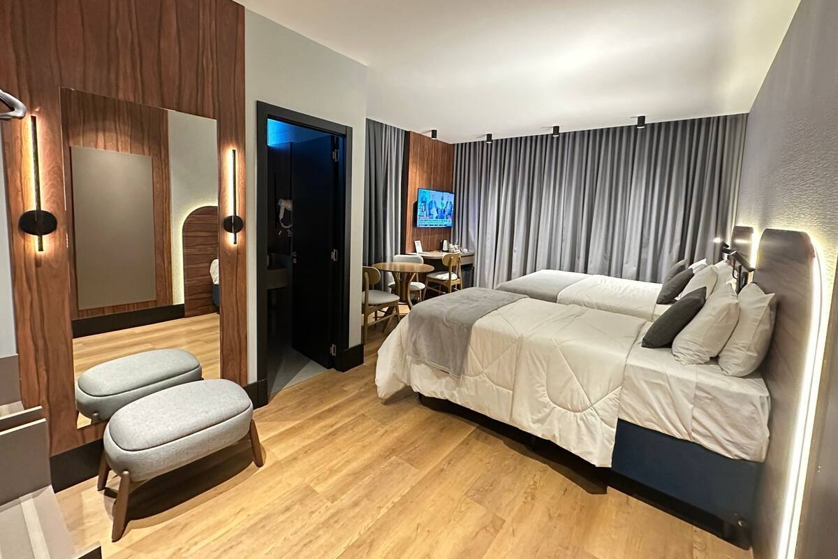 A modern hotel room with a large bed, a desk, and a TV.