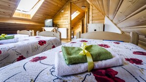 Una cabaña de madera acogedora con dos camas, cada una con ropa de cama y toallas estampadas.