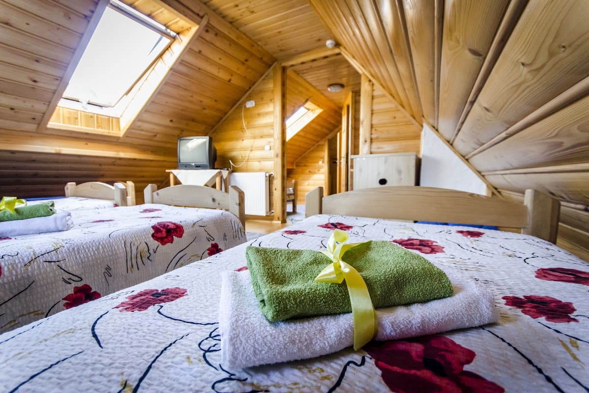 Una cabaña de madera acogedora con dos camas, cada una con ropa de cama y toallas estampadas.