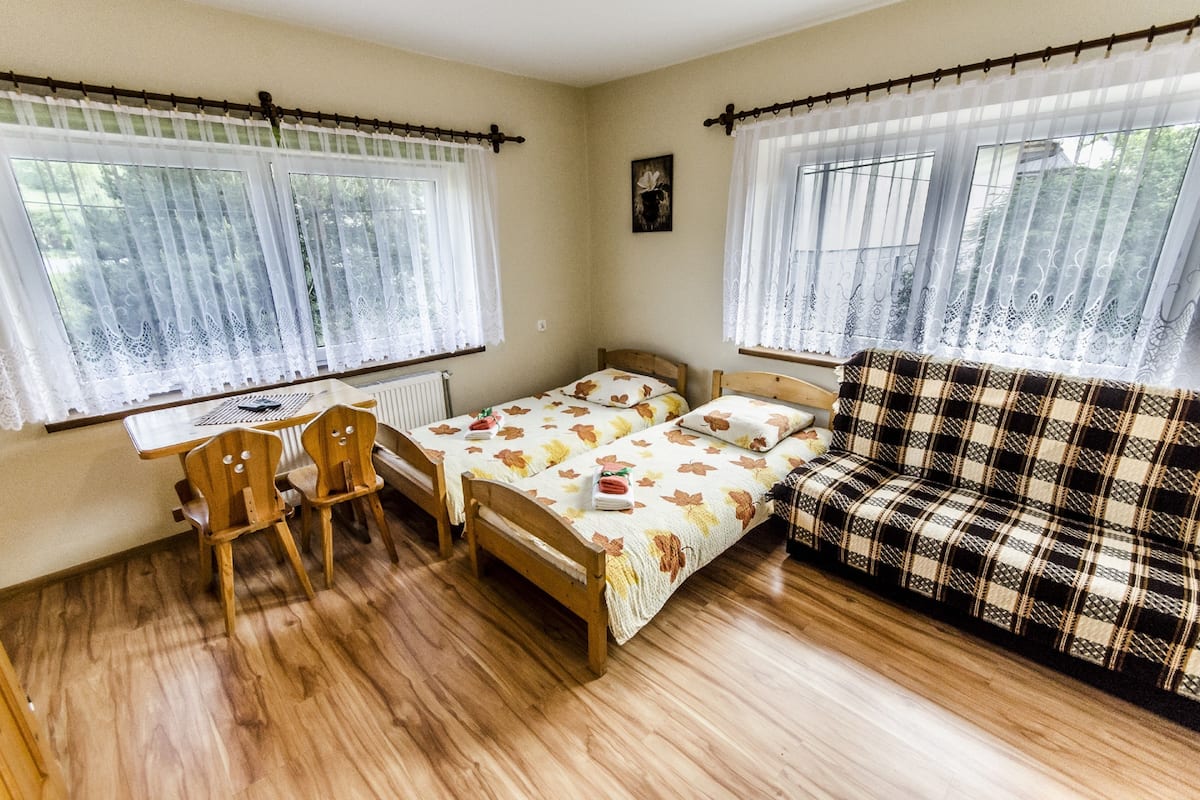 Una habitación con dos camas de madera, un sofá, una mesa y sillas.