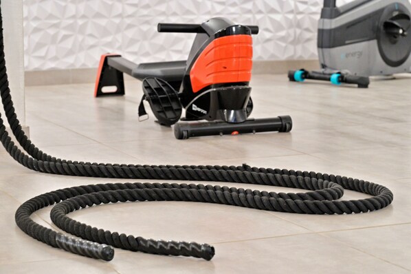 A stationary exercise bike with a coiled resistance band on the floor.