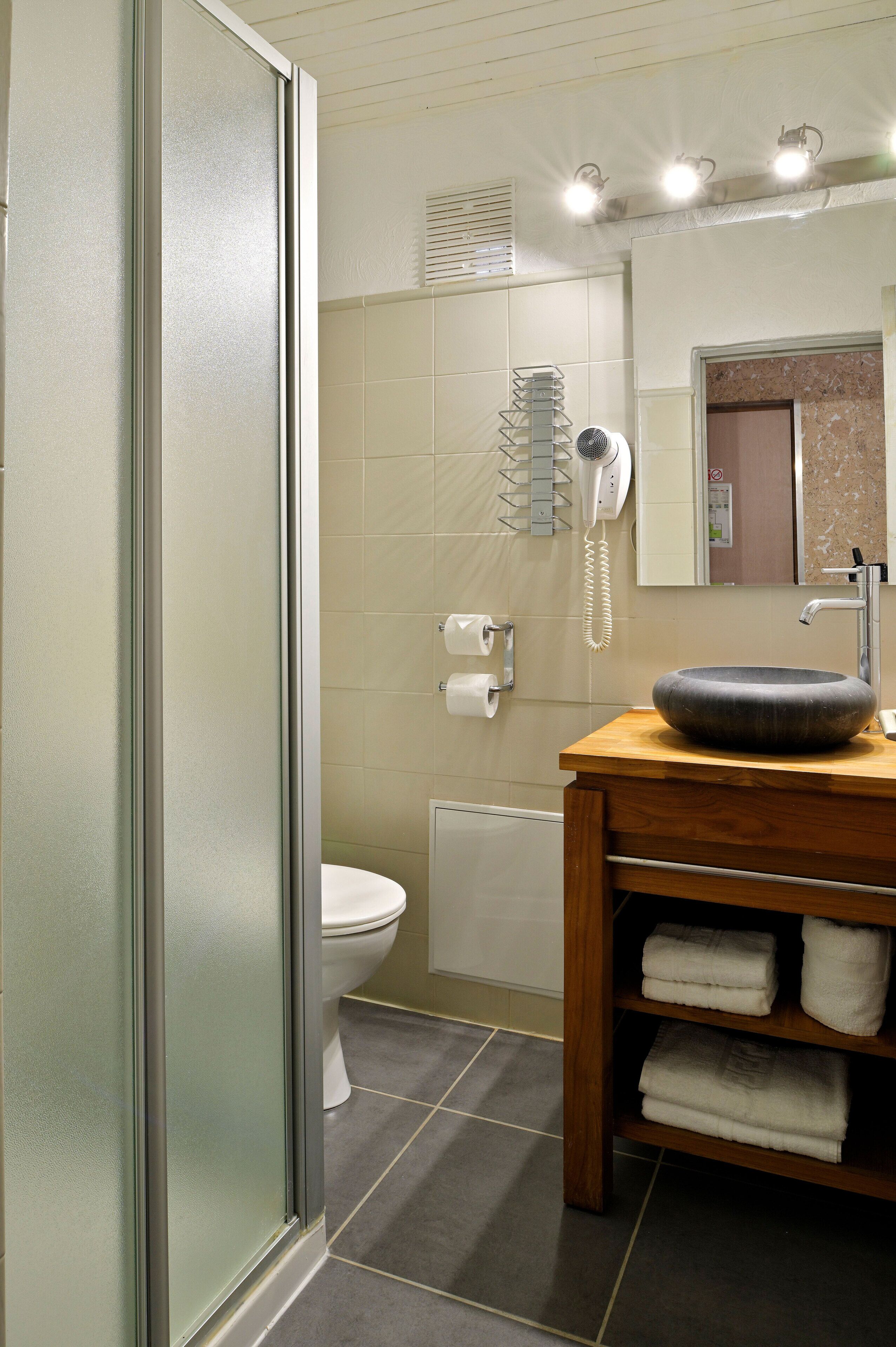 Un bagno con box doccia in vetro, un water, un lavandino e un portascopino.