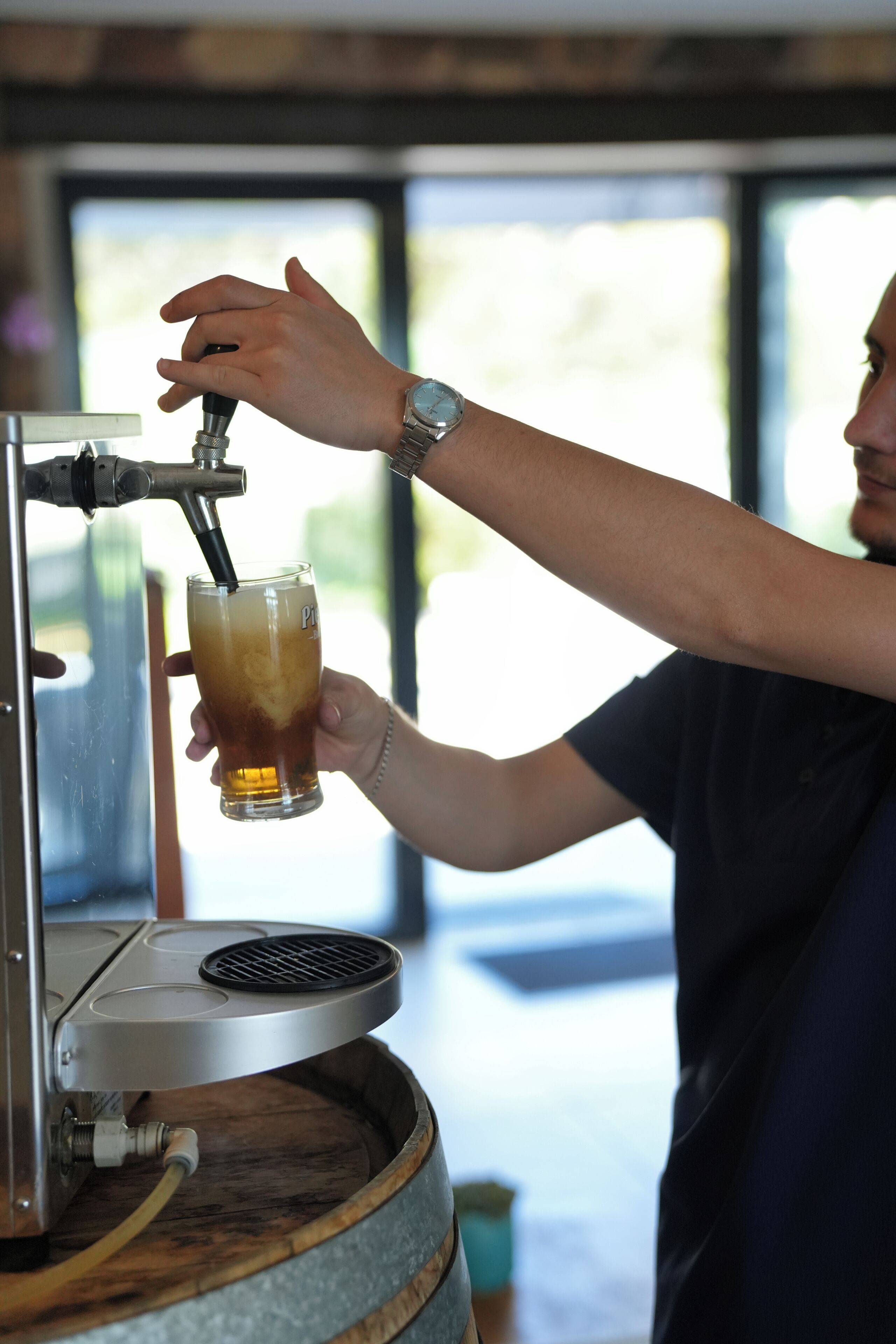 A person pouring a drink from a tap into a glass.