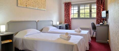 A hotel room with two beds, a desk with a computer, a chair, and a window with curtains.