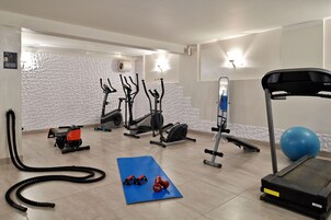 Uma academia com equipamentos de ginástica, um colchonete azul e uma esteira.