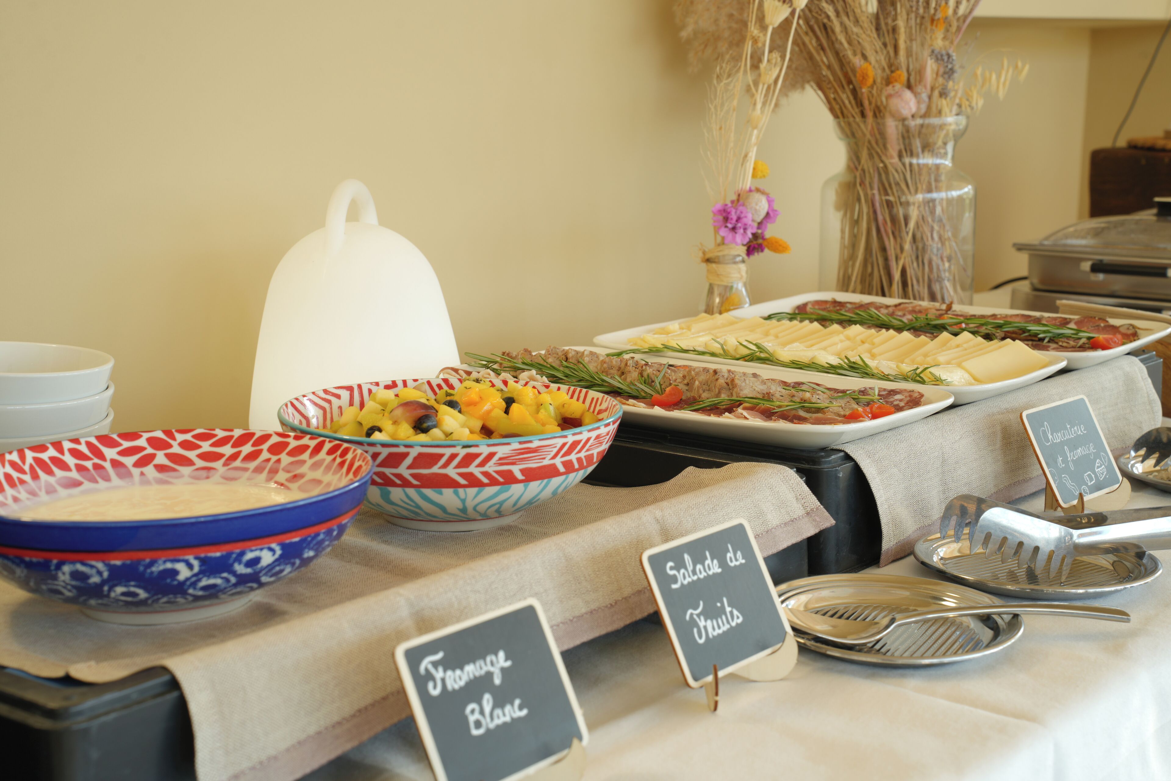 Una mesa de bufé con platos etiquetados, incluyendo 'Fromage Blanc' y 'Salade de Fruits'.