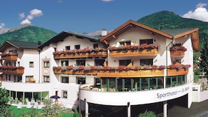 Un hotel de varios pisos con balcones decorados con flores, un letrero que dice 
