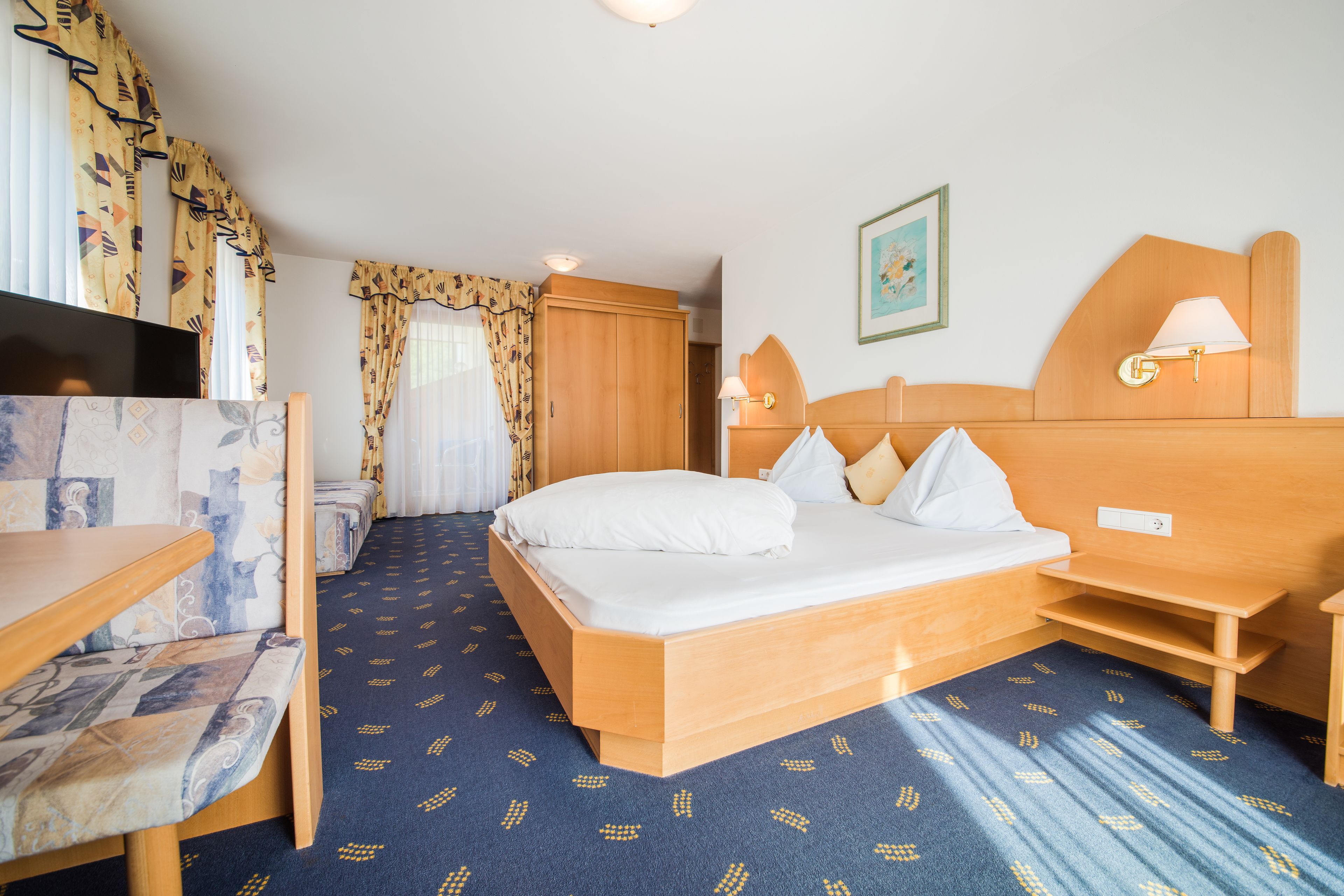 Ein Hotelzimmer mit einem Bett, einem Schreibtisch, einem Sessel, einem Fernseher und einem Kleiderschrank.
