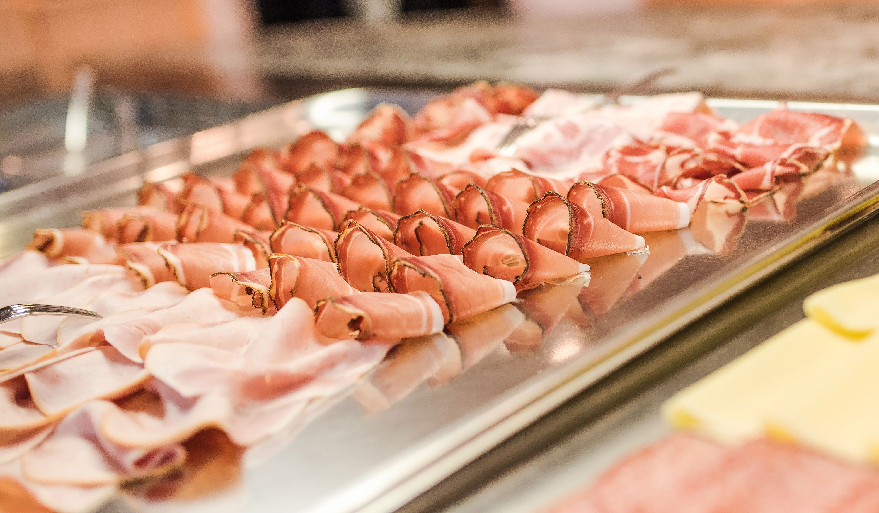 A display of various cured meats, including prosciutto and salami, arranged on a metal tray.