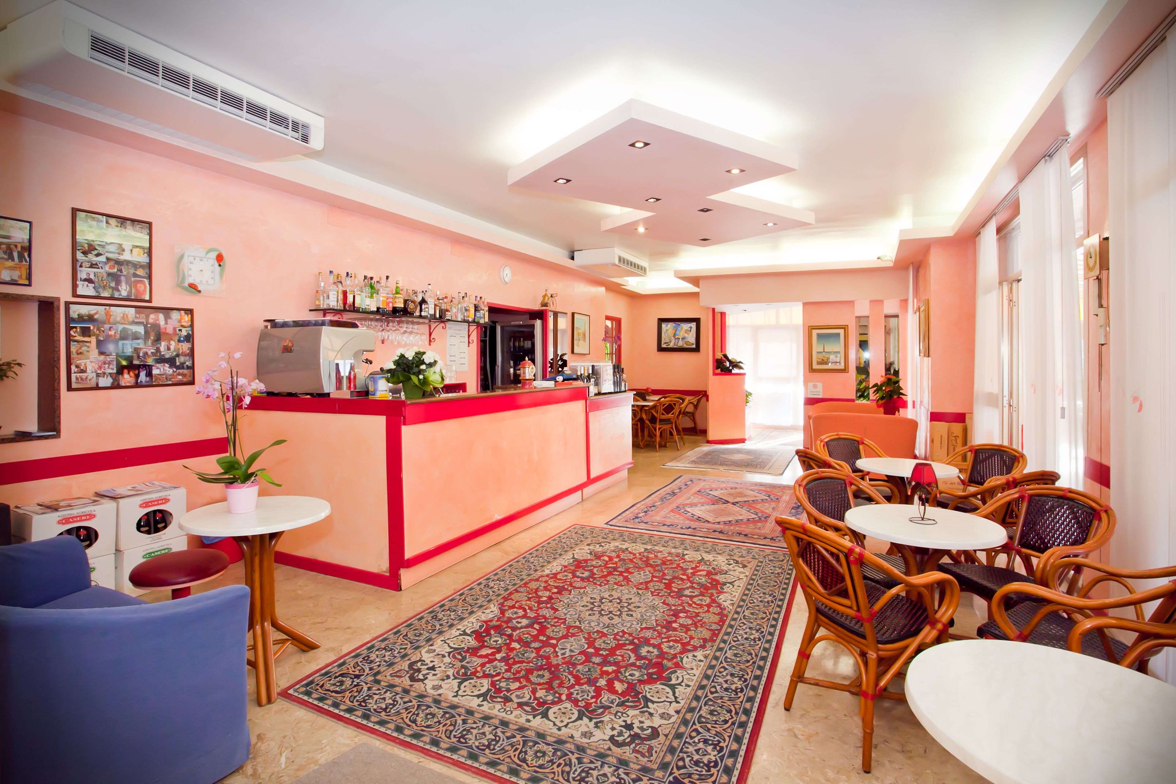 A hotel lobby with a reception desk, seating area, and a large decorative rug.