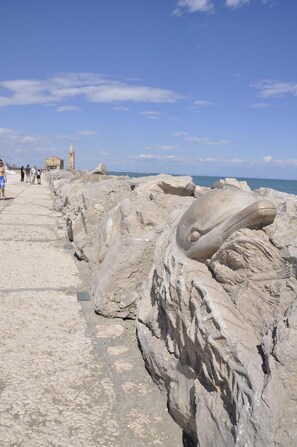 A rocky coastal walkway with large boulders and a distant building. - Hotel Catto Suisse (Caorle)