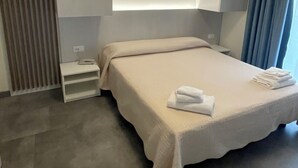 A modern hotel room with a neatly made bed, a bedside table, and a built-in wardrobe. - Hotel Catto Suisse (Caorle)