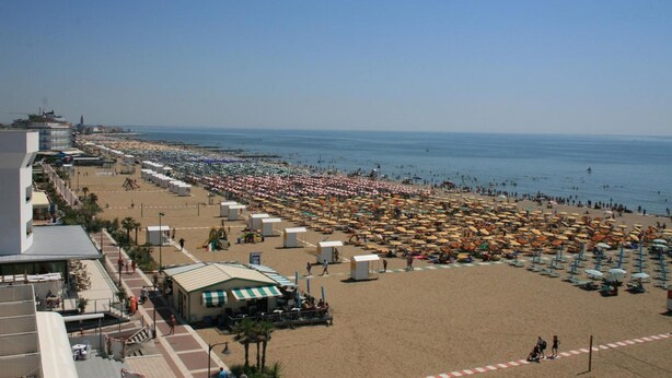 A beach with numerous umbrellas and sun loungers, a clear sky, and a view of the sea. - Hotel Catto Suisse (Caorle)