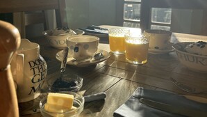 A breakfast table with various items including mugs, glasses, and a bowl of butter. - South Craighall Bed & Breakfast (Glasgow)