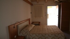 A bedroom with a bed, bedside table, and a door leading to a balcony. - Agritur Ponte Alto (Trento)