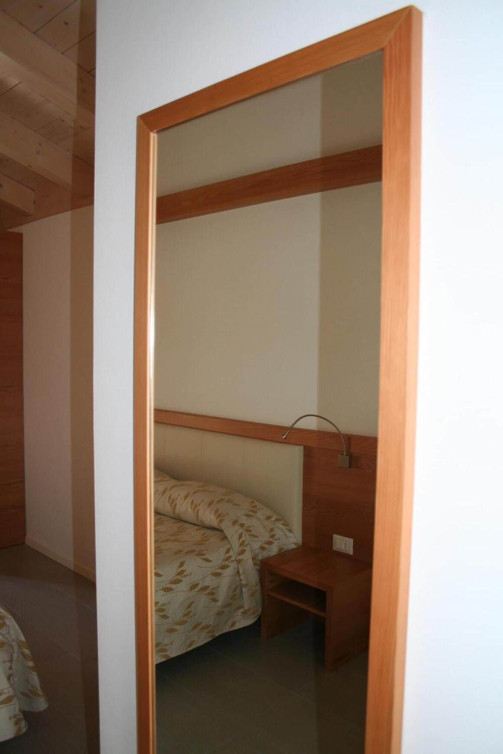 Una stanza con un letto a castello, un comodino di legno e una lampada fissata al muro.