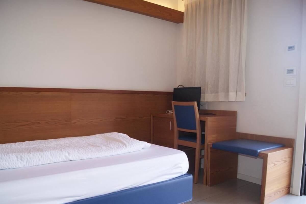 A bedroom with a bed, a desk, and a chair.