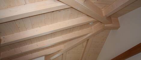 Una habitación con vigas de madera a la vista y techo inclinado.