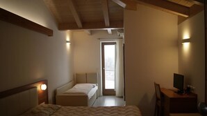 A bedroom with a bed, a desk, and a chair. There is a door leading to a balcony. - Agritur Ponte Alto (Trento)
