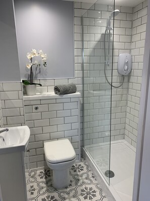 A bathroom with a toilet, sink, and shower area. - Serviced Apartments East Kilbride (Glasgow)