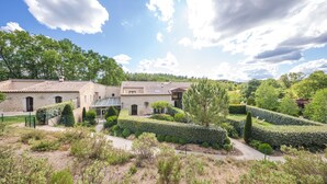 A villa with a courtyard, surrounded by lush greenery and a clear sky. - Le Relais du Grand Logis Cadarache ITER (Mirabeau)