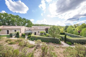 Una villa con patio, rodeada de abundante vegetación y un cielo despejado.
