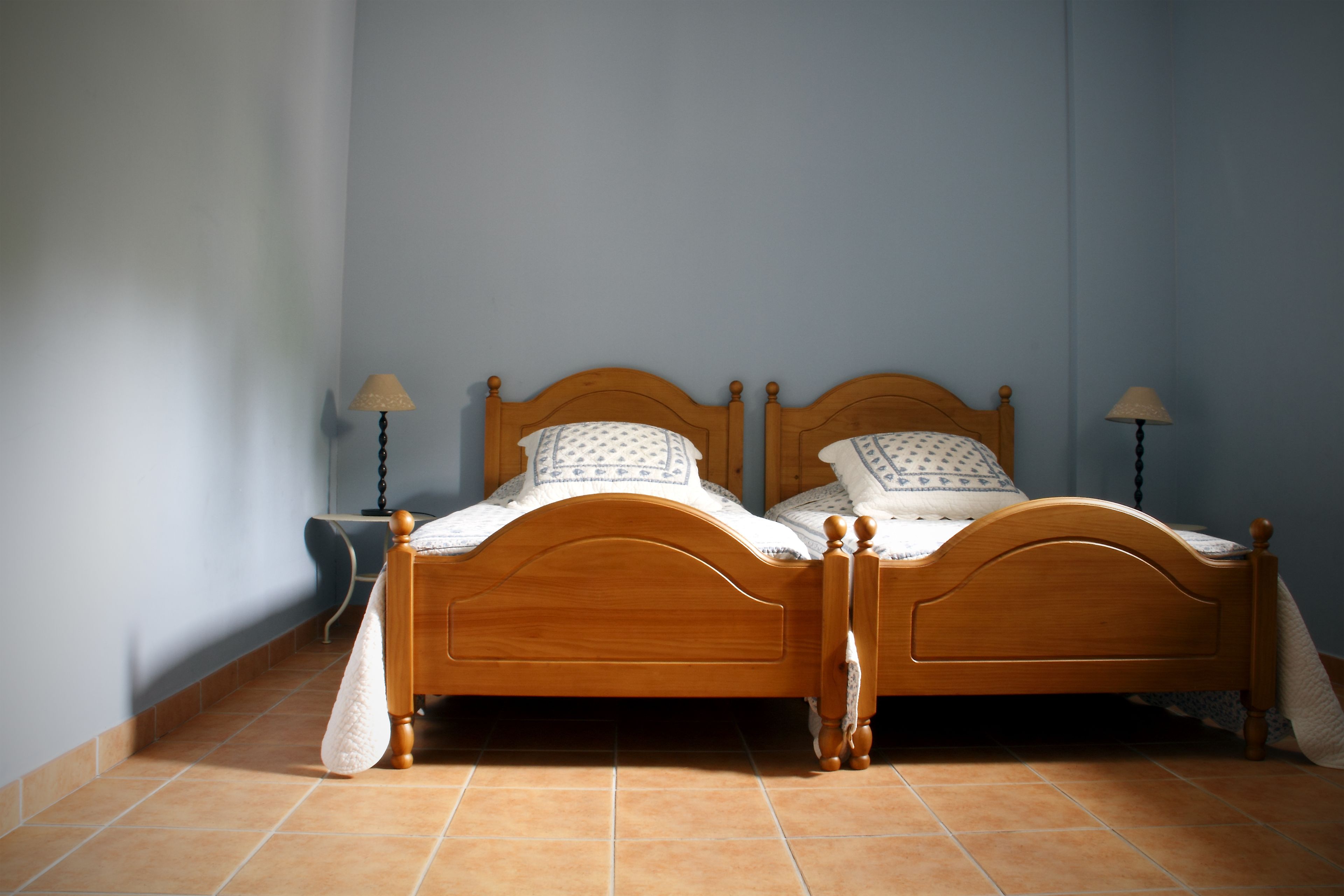 Una cama doble de madera con cabecera, dos mesitas de noche y lámparas.