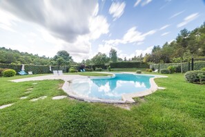A swimming pool surrounded by well-maintained grass and hedges, with a clear sky above. - Le Relais du Grand Logis Cadarache ITER (Mirabeau)